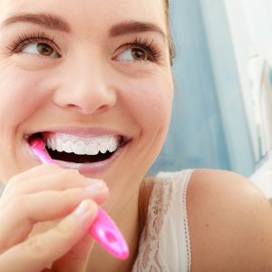Young woman brushing cleaning teeth. Girl with toothbrush in bathroom. Oral hygiene.