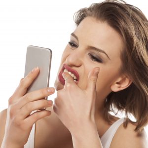 girl cleans stains on her teeth looking in the smartphone
